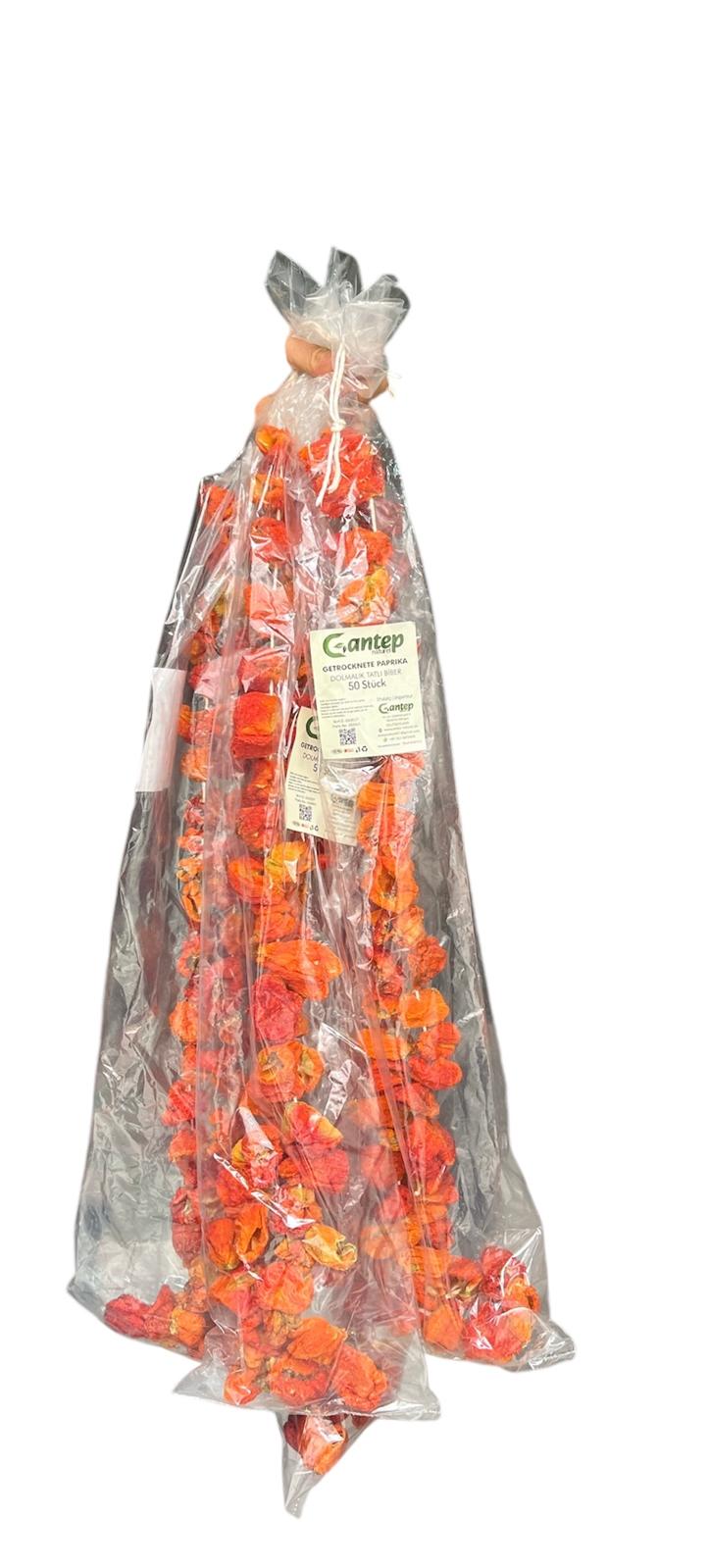 Verpackung mit 50 milden, getrockneten Paprikaschoten von Gantep Naturel, in transparenter Folie mit grünem Etikett „Dolmalık Tatlı Biber“, auf hellem Hintergrund stehend aufgenommen.