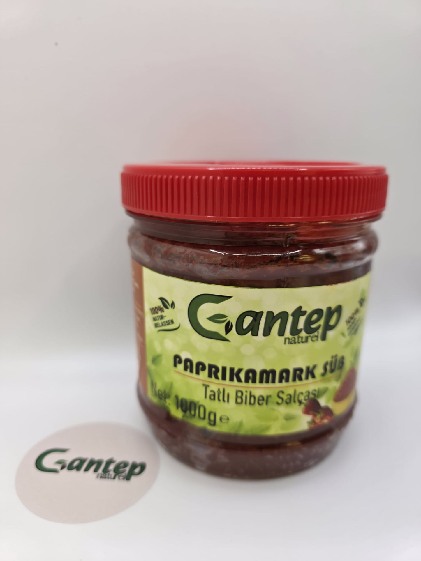Gantep Naturel milder Paprikamark im 1000-g-PET-Behälter mit rotem Schraubdeckel; Frontansicht des Etiketts mit grünem Hintergrund und Produktbezeichnung „Tatlı Biber Salçası“, fotografiert auf hellem Hintergrund.