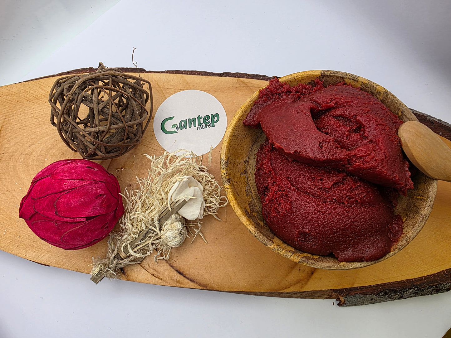 Perspektive von oben auf angerichtetes Tomatenmark von Gantep Naturel in einer Holzschale mit natürlicher Deko auf Holzbrett.