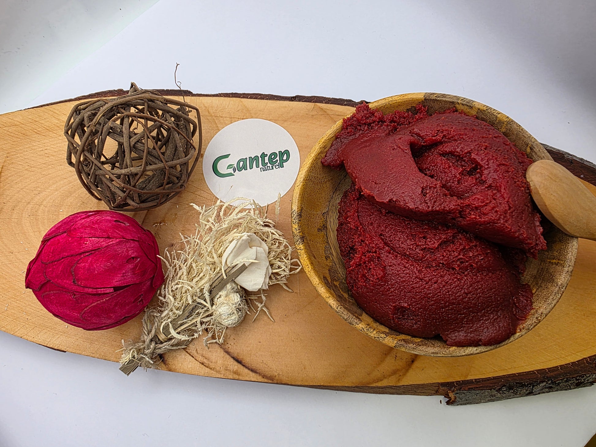 Perspektive von oben auf angerichtetes Tomatenmark von Gantep Naturel in einer Holzschale mit natürlicher Deko auf Holzbrett.