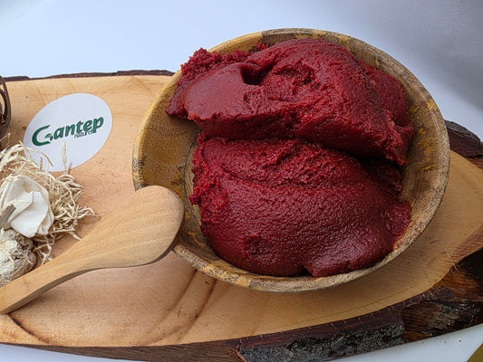 Gantep Naturel Tomatenmark angerichtet in einer Holzschale auf einem dekorativen Holzbrett mit Naturmaterialien.